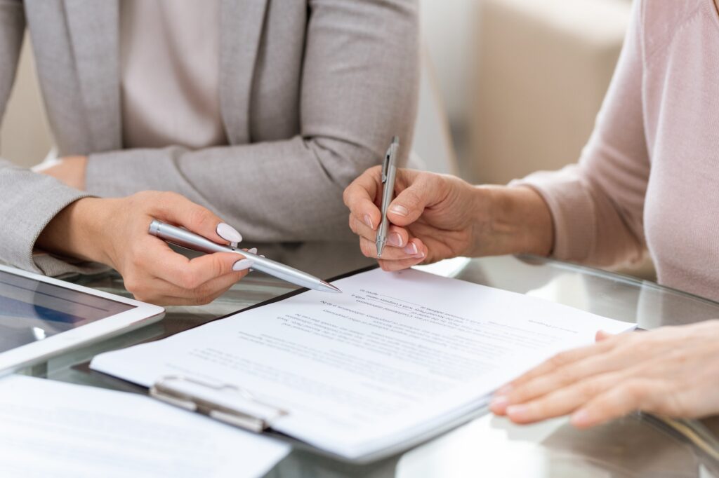 Two businesswomen consulting or discussing terms of contract at meeting